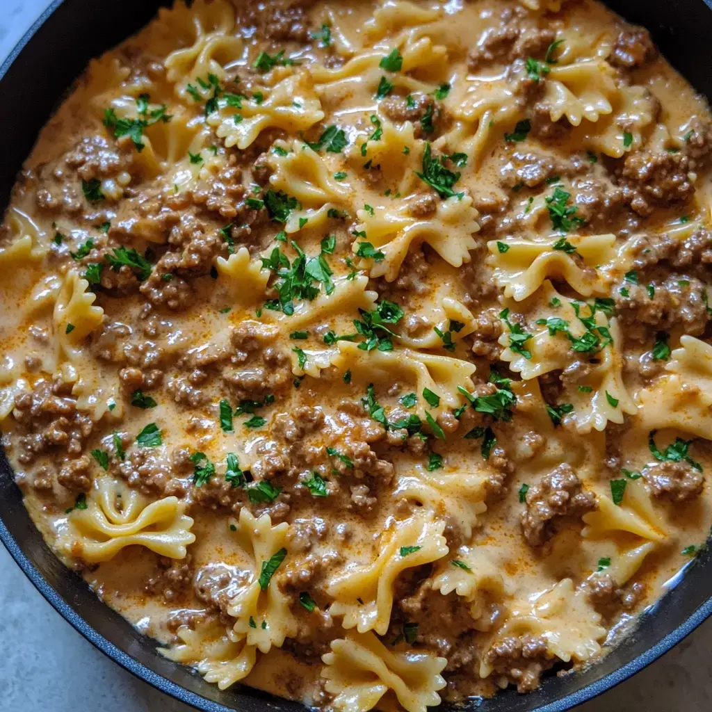 A steaming bowl of creamy farfalle pasta mixed with seasoned ground beef and topped with fresh parsley.