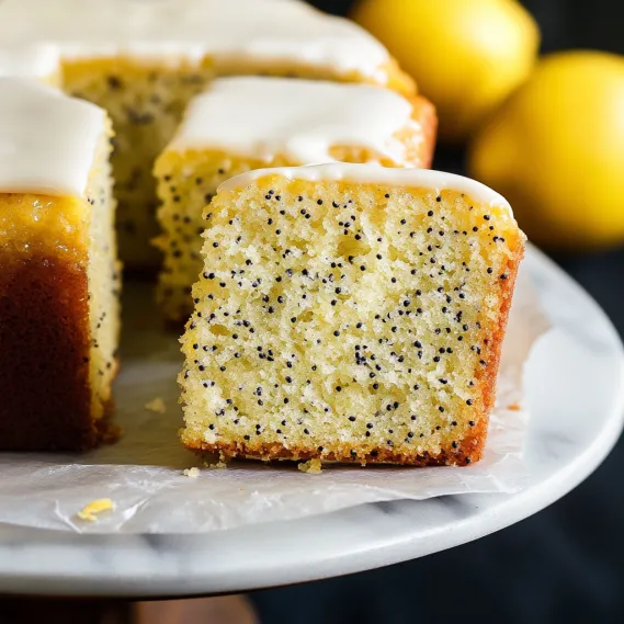 A moist cake slice with white frosting and tiny black seeds.