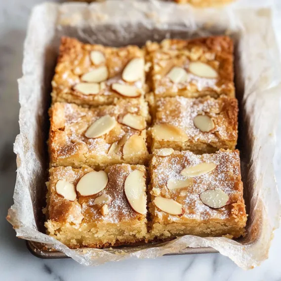 A box of almond cake with powdered sugar on top.