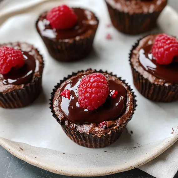 Chocolate cupcakes with raspberries on top.