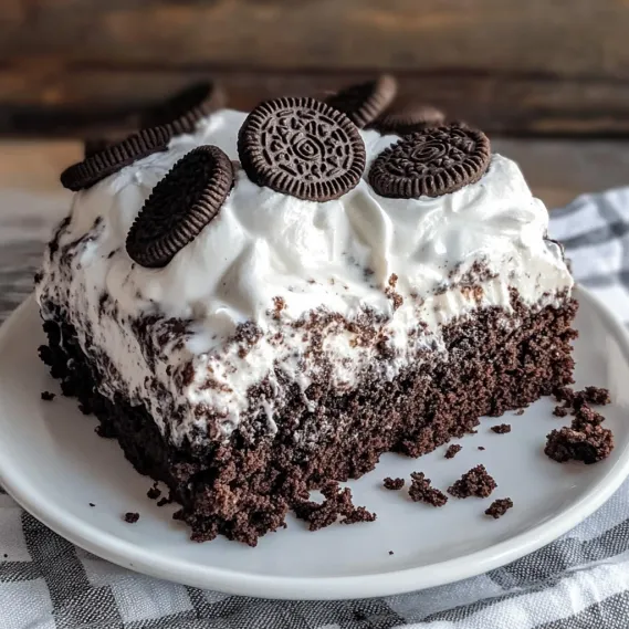 A chocolate cake slice with creamy frosting and chocolate chip bits.