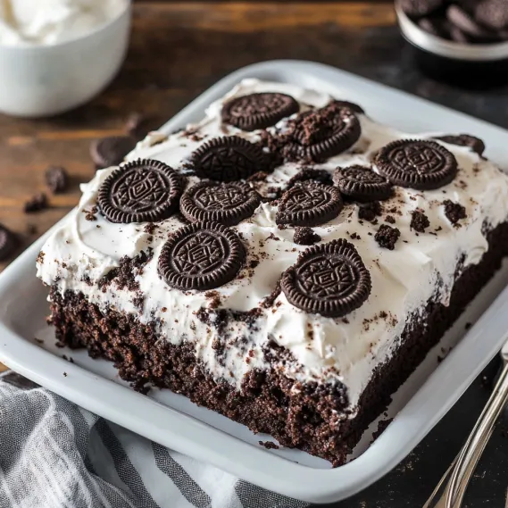 A slice of chocolate cake with white frosting and chocolate chips.
