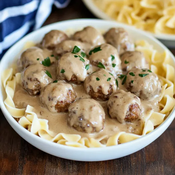 A bowl of food with noodles and meatballs.
