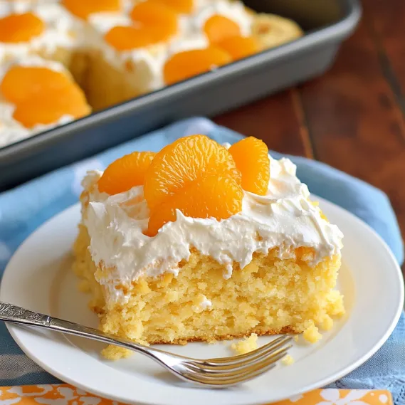 A fluffy white-frosted cake slice topped with orange mandarin pieces.