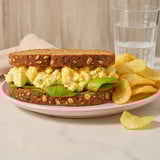 A loaded sandwich next to chips.