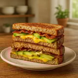A plate of toasted sandwich with avocado and bacon filling.