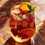 A refreshing glass of white sangria with strawberries, mint, and orange garnish.