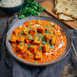 A dish of creamy tofu tikka masala with toppings.