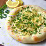 A pizza with citrus slices and herbs on top.