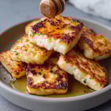 Plate filled with golden air-fried halloumi covered in sweet honey.