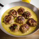 A skillet of meatballs with lemon sauce.