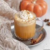 Pumpkin spice milk in a glass topped with whipped cream.
