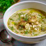 A cozy bowl of creamy cauliflower soup with herbs.