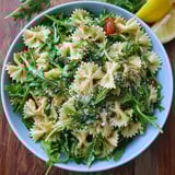 A fresh pasta bowl topped with arugula and lemon dressing.